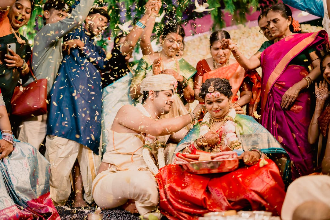 Family throws petals and rice over the bride and groom during a joyful ritual.